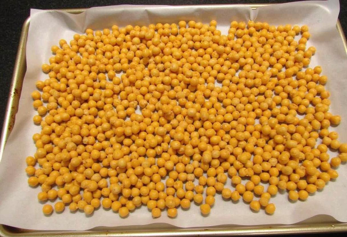 Seasoned chickpeas arranged on a baking sheet, prepared for roasting until crispy.