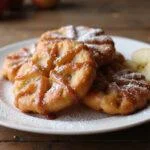 Deliciously sweet glazed apple fritters presented on a rustic wooden table, highlighting a mouthwatering apple fritter recipe.