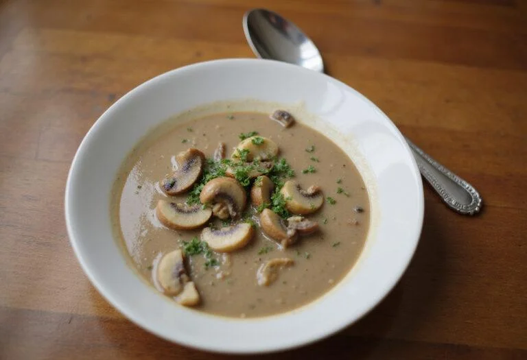 Delicious dairy free cream of mushroom soup served in a bowl, garnished with herbs, perfect for a warm and comforting meal.
