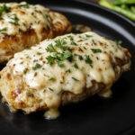 A close-up of a plated creamy garlic parmesan chicken pasta dish, featuring tender chicken pieces coated in a rich, creamy white sauce with specks of grated parmesan and herbs, arranged on a rustic plate. The pasta is twisted and al dente, garnished with fresh parsley, with a warm, inviting presentation.