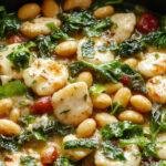 A close-up shot of a vibrant white bean and spinach skillet, featuring creamy white beans intertwined with fresh, bright green spinach leaves, garnished with a sprinkle of herbs, served in a rustic skillet with a golden crust around the edges, steam gently rising, highlighting a warm and inviting dish.